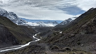 Snowy Andes Mountain Valley with River and Winding Road