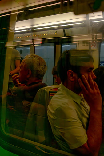 Commuters on subway train through window reflection