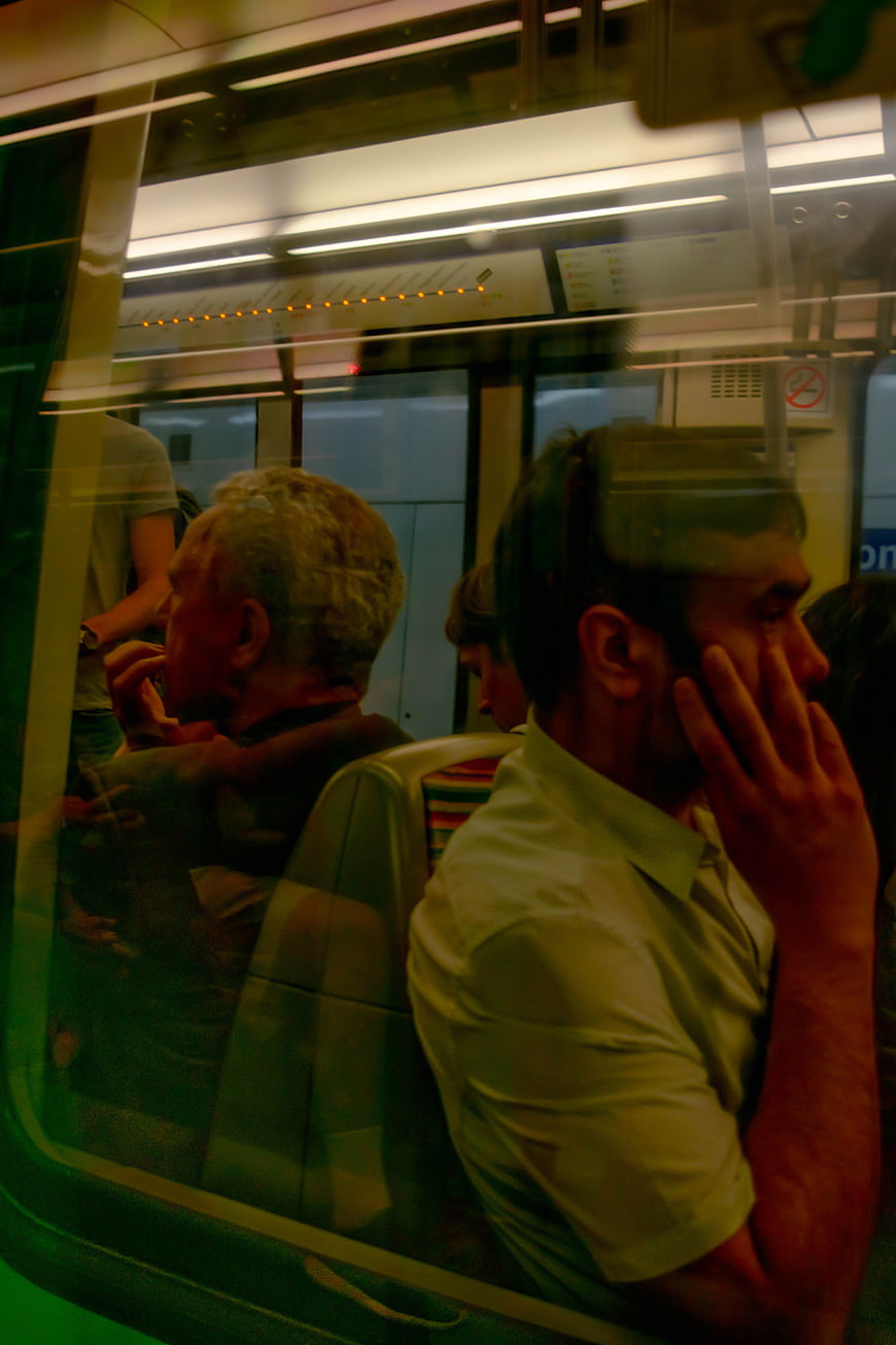 Commuters on subway train through window reflection