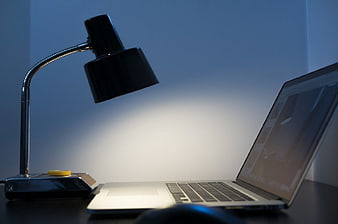 Modern laptop and desk lamp on dark workspace