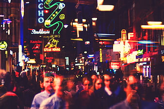 Vibrant neon street scene with blurred pedestrians at night in a busy urban district