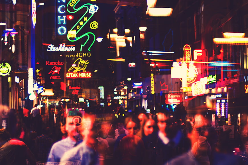 Vibrant neon street scene with blurred pedestrians at night in a busy urban district