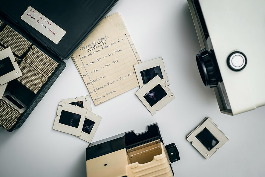 Vintage slide film strips and projector on white background