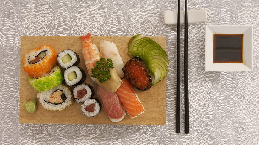 Overhead view of assorted sushi platter with soy sauce and chopsticks
