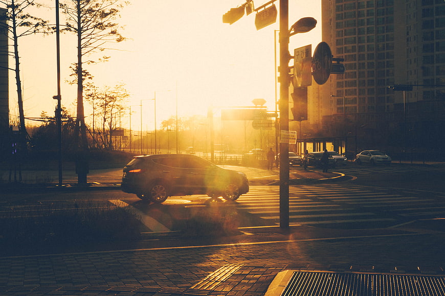 SUV Driving Through City Intersection at Golden Hour Sunset