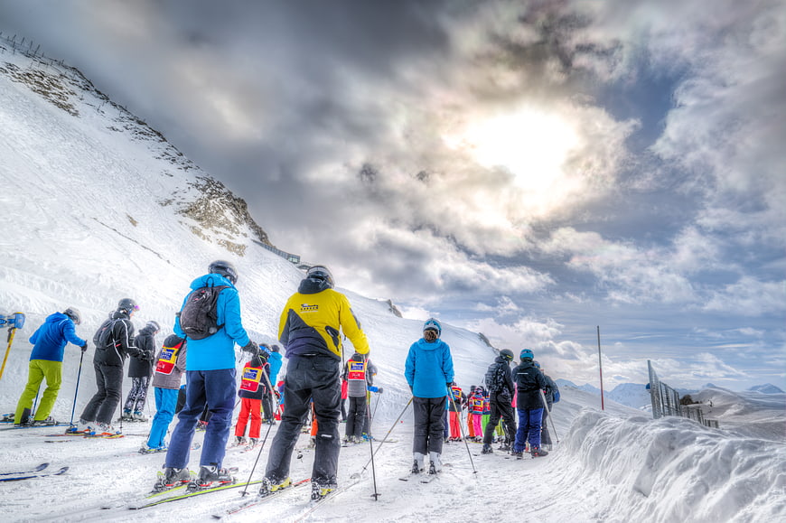 Group of Skiers on Snowy Mountain Slope Under Dramatic Sky