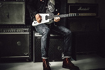 Rock Musician Playing White Electric Guitar on Amplifiers