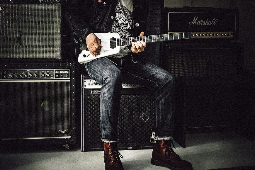 Rock Musician Playing White Electric Guitar on Amplifiers