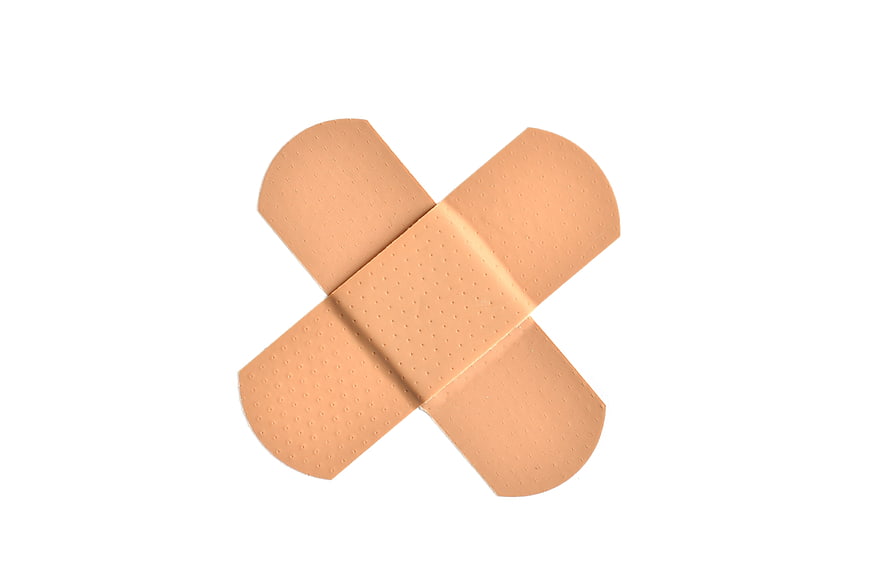 Two beige adhesive bandages crossed on white background