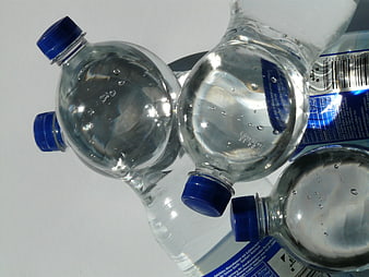 Close-up of plastic water bottles with blue caps on white background