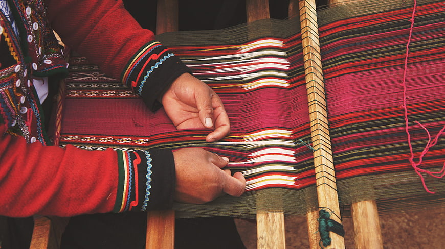 Close-up of hands weaving colorful traditional textile on loom