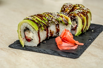 Avocado Topped Sushi Rolls With Sesame Seeds And Ginger On Slate