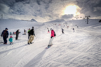Snowboarders on Alpine Slope with Dramatic Cloudy Sky