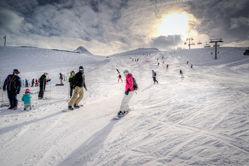 Snowboarders on Alpine Slope with Dramatic Cloudy Sky