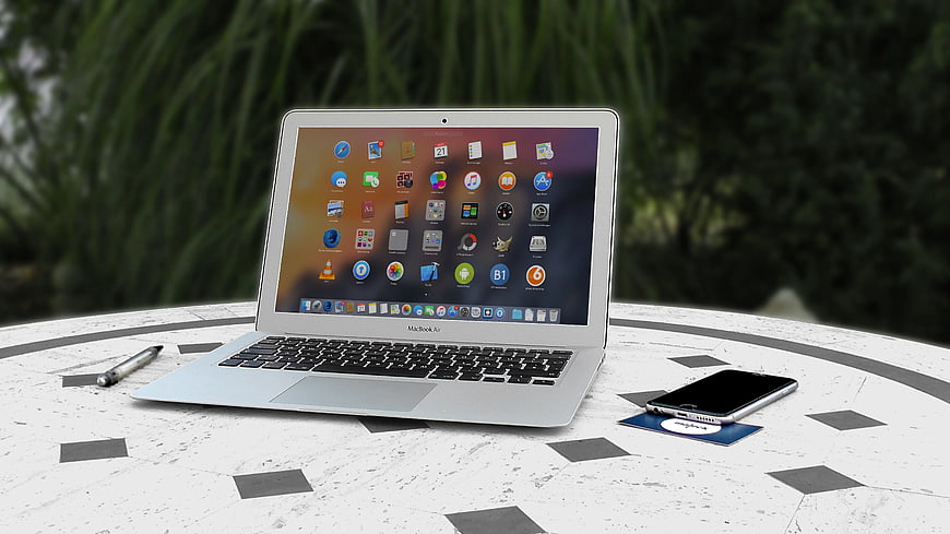 Silver MacBook Air on Outdoor Table with Smartphone