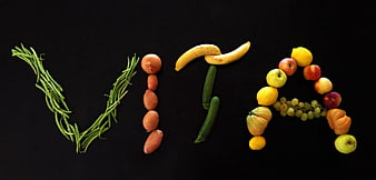 VITA word spelled with fresh fruits and vegetables on black background