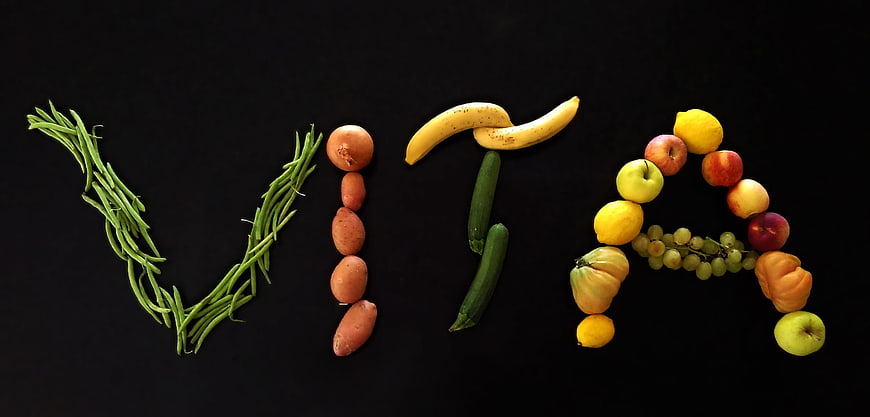 VITA word spelled with fresh fruits and vegetables on black background