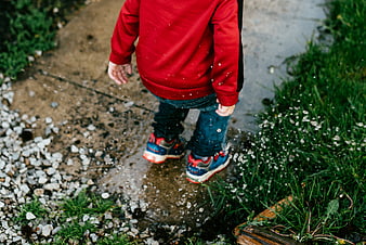 Child jumping in puddle splashing water
