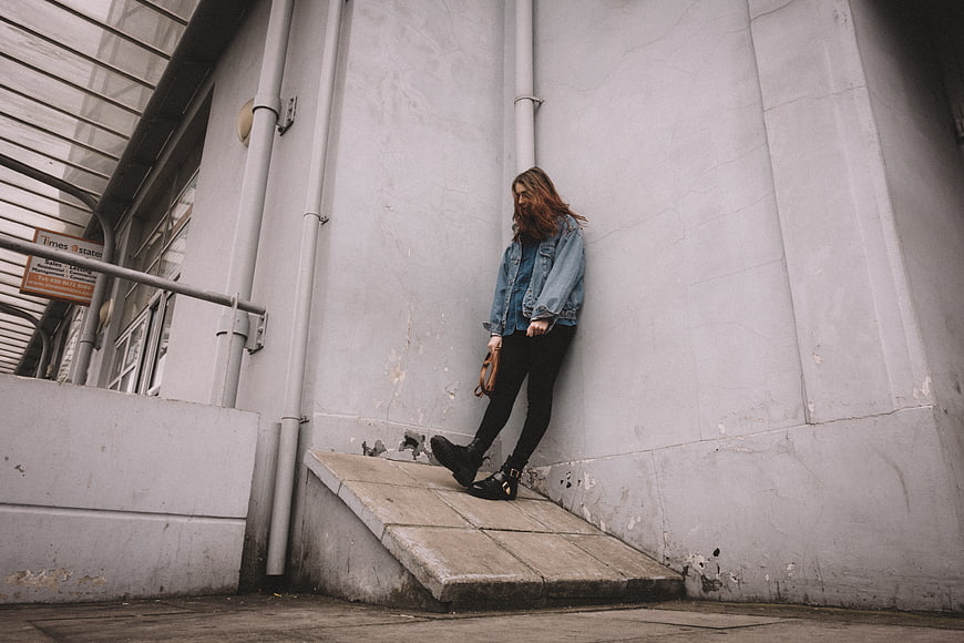 Woman in Denim Jacket Leaning Against Urban Wall