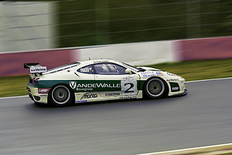 White and Green Race Car Speeding on Track