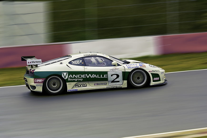 White and Green Race Car Speeding on Track