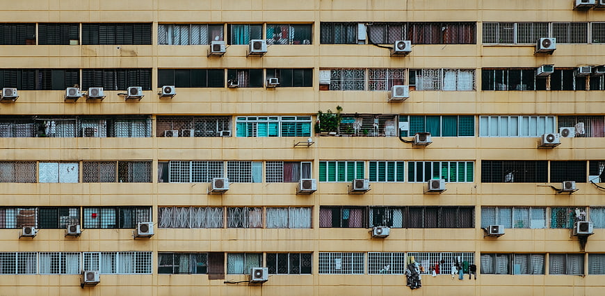 Yellow Apartment Building Facade With Air Conditioners And Windows