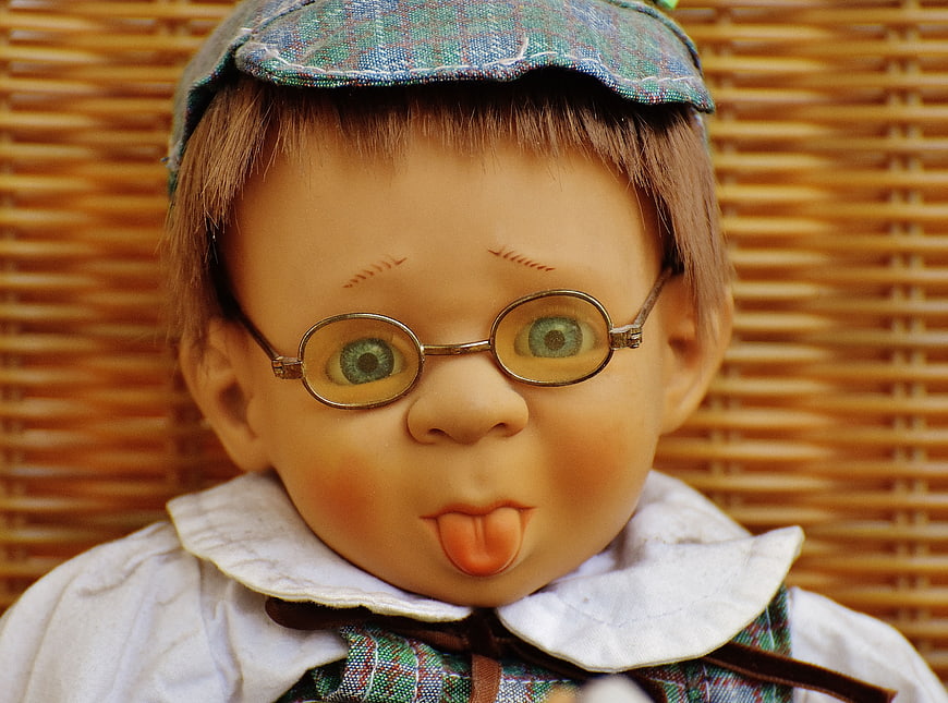Vintage Doll with Glasses and Plaid Cap Sticking Tongue Out