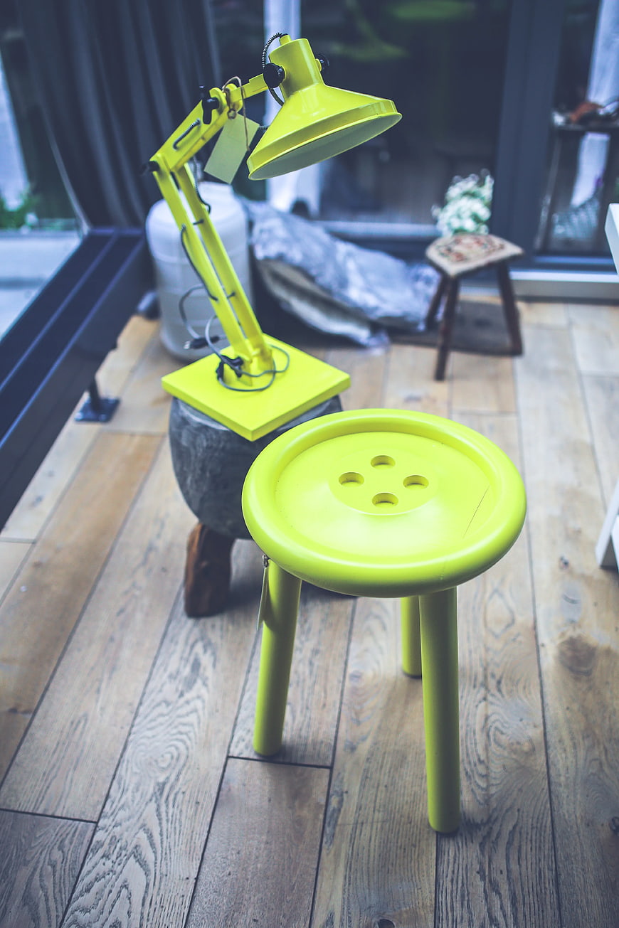 Lime green button stool and desk lamp on wooden floor