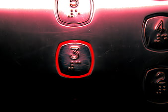 Close-up of metallic elevator button number 3 with red ring