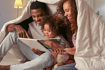 Happy African American Family Reading Book Under Blanket Fort