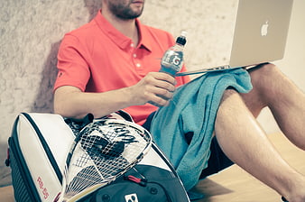 Male athlete with squash racket and laptop