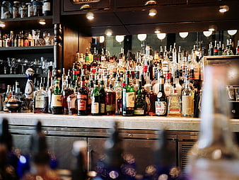 Well-stocked bar counter with liquor bottles and bokeh lights