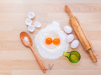 Flat lay of baking ingredients with flour, eggs, and rolling pin