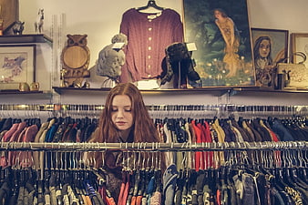 Woman with red hair browsing clothes in vintage shop