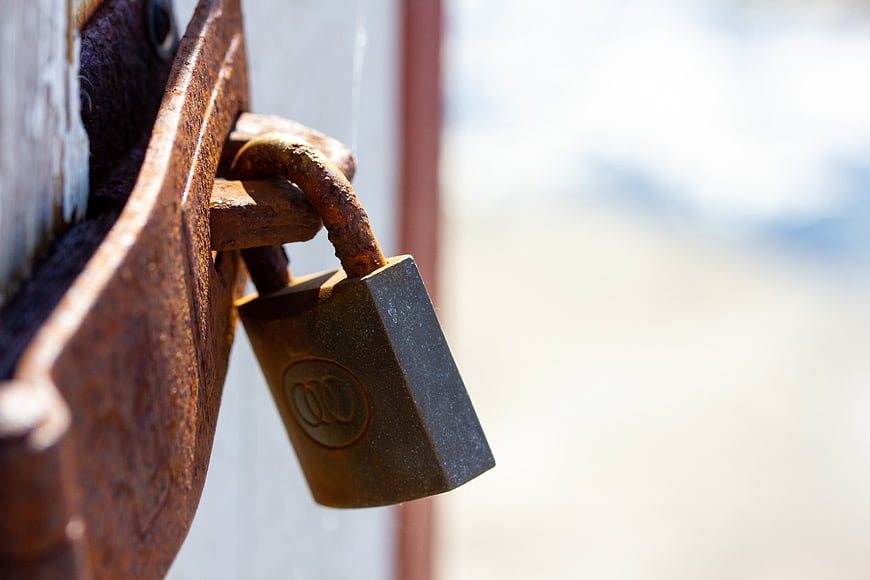 Close-up of rusty padlock on weathered metal gate