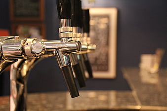 Close-up of chrome beer tap handles in a dimly lit bar