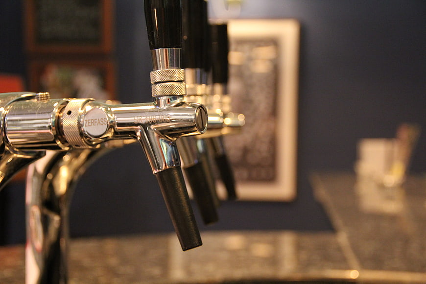 Close-up of chrome beer tap handles in a dimly lit bar