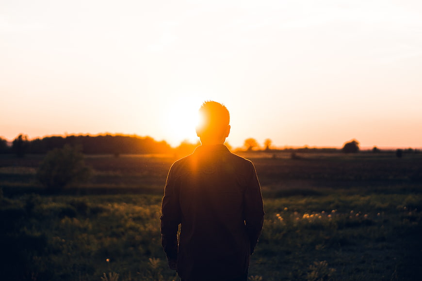 Silhouette of Man Standing in Field at Sunset