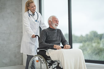Female Doctor Pushing Senior Man in Wheelchair