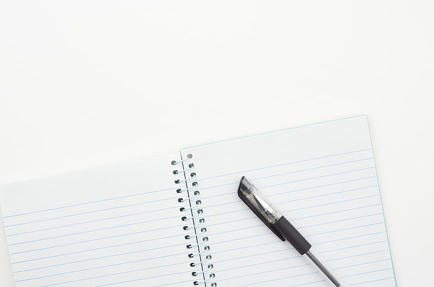 Blank spiral notebook and pen on white background