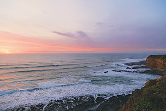 Serene Sunset Over Rocky Coastline with Ocean Waves