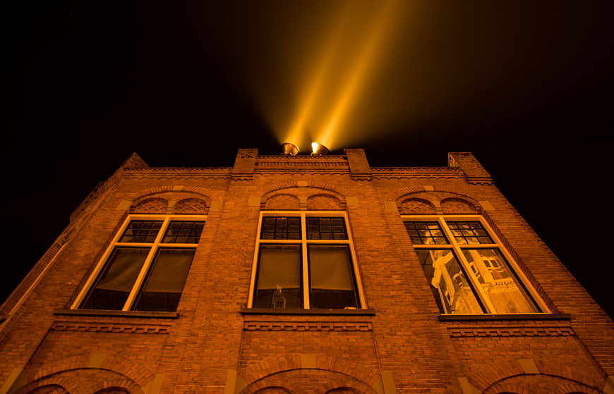 Low angle view of brick building with rooftop spotlights at night
