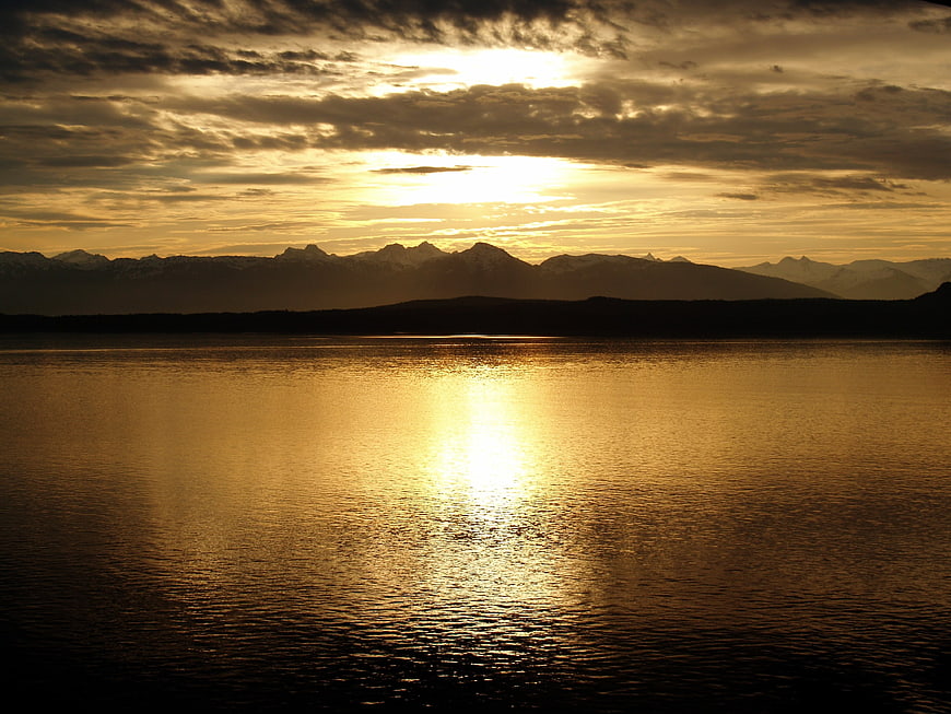 Golden sunset over calm lake with mountain silhouette