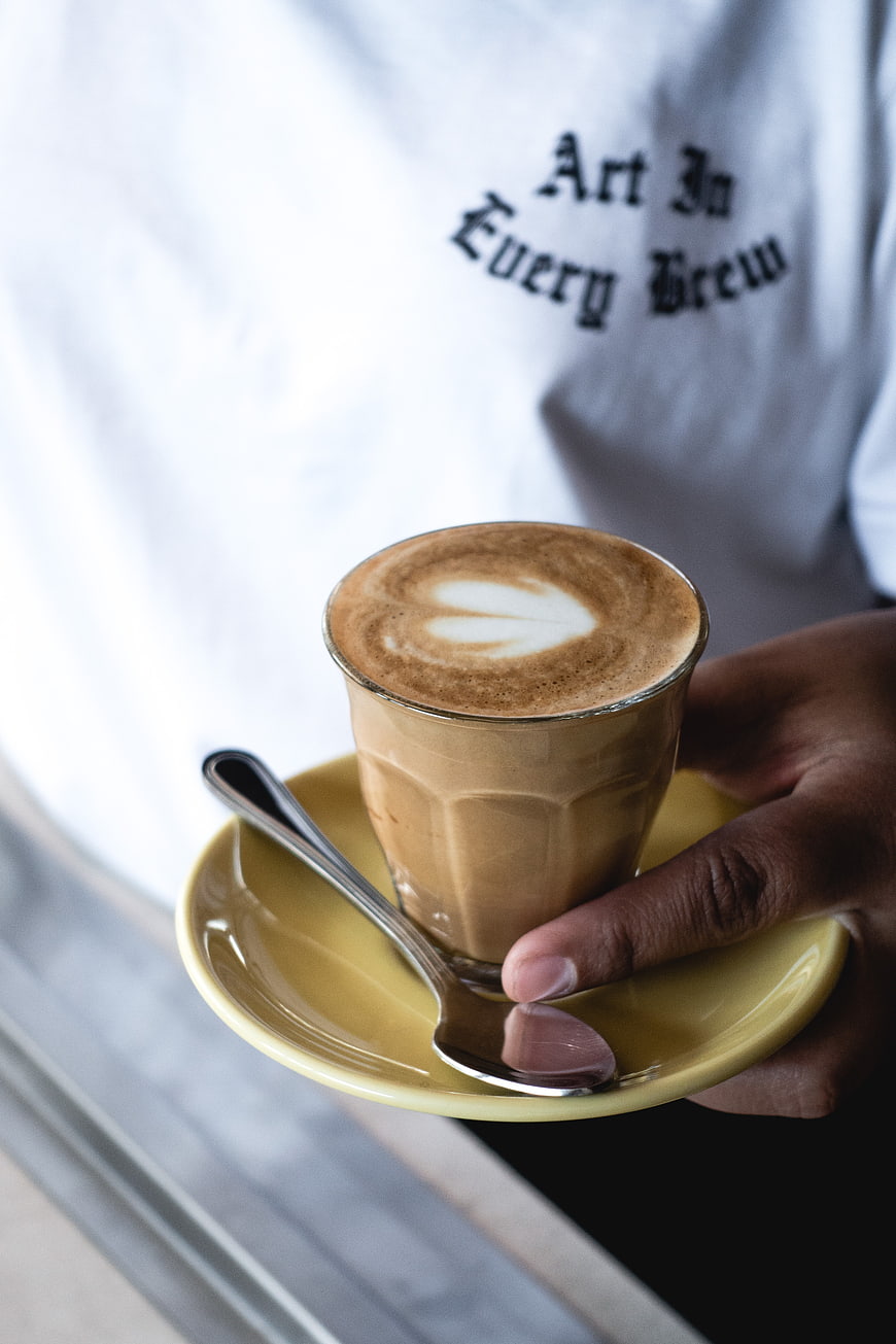 Barista holding flat white coffee with latte art