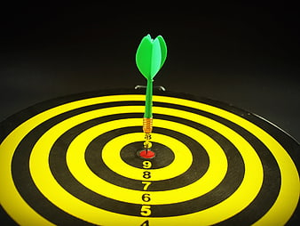 Green Dart Hitting The Bullseye On A Yellow And Black Dartboard