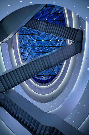 Modern spiral staircase with blue glass ceiling and geometric design