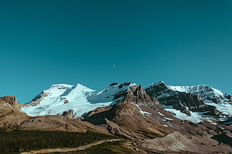 Snow-Capped Mountain Peaks Under Teal Sky with Crescent Moon