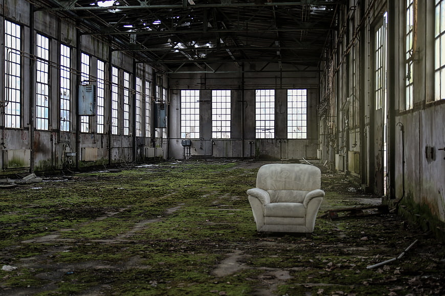 Abandoned Factory Interior with Mossy Floor and White Armchair