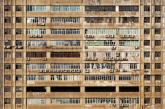 Weathered concrete apartment building facade with windows and air conditioners