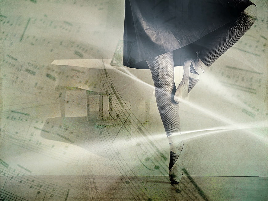 Ballerina legs in pointe shoes with sheet music background